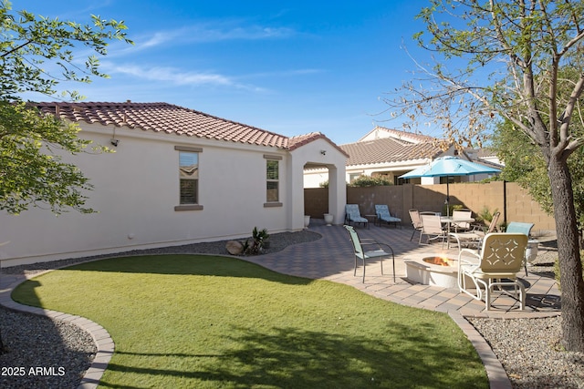 back of property featuring a yard, a patio, and an outdoor fire pit