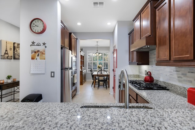 kitchen with extractor fan, sink, light stone counters, tasteful backsplash, and appliances with stainless steel finishes