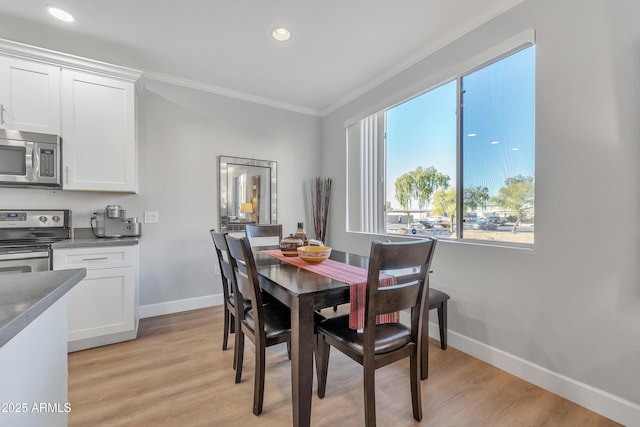 dining space featuring ornamental molding and light hardwood / wood-style floors