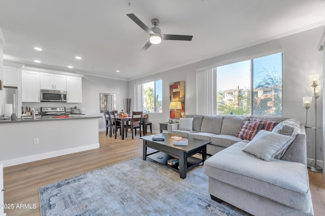 living room featuring light hardwood / wood-style flooring, ornamental molding, and ceiling fan