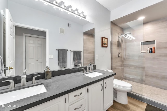 bathroom featuring vanity, hardwood / wood-style flooring, a shower with door, and toilet