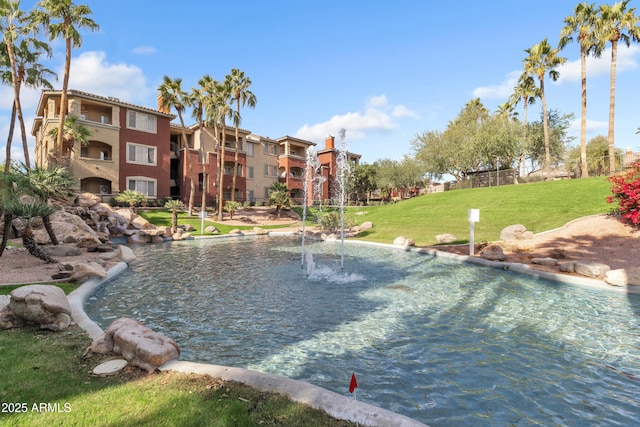 view of pool with a water view and a lawn