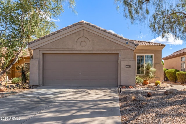 view of front facade with a garage, concrete driveway, a tile roof, and stucco siding