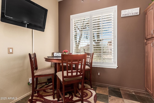 dining room with stone tile flooring and baseboards