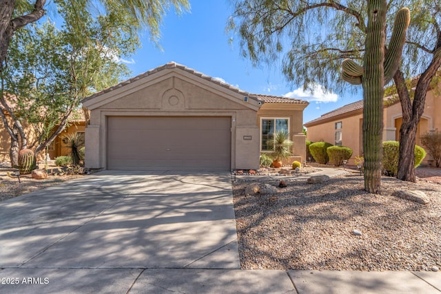 view of front of property featuring concrete driveway, an attached garage, a tiled roof, and stucco siding