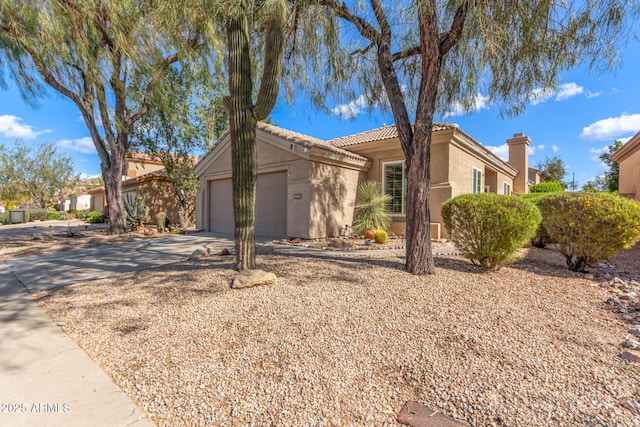 single story home featuring a chimney, stucco siding, a garage, driveway, and a tiled roof