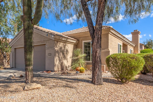 view of front of property with driveway, a chimney, an attached garage, and stucco siding