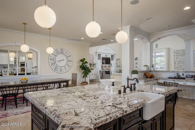 kitchen featuring dark brown cabinets, hanging light fixtures, crown molding, and sink