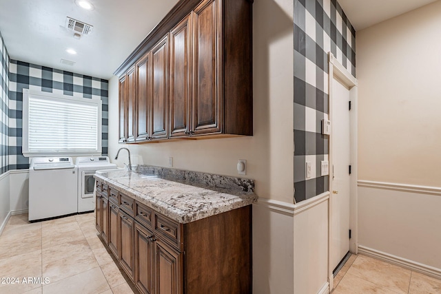 kitchen featuring light stone counters, washer and clothes dryer, light tile patterned flooring, and dark brown cabinets