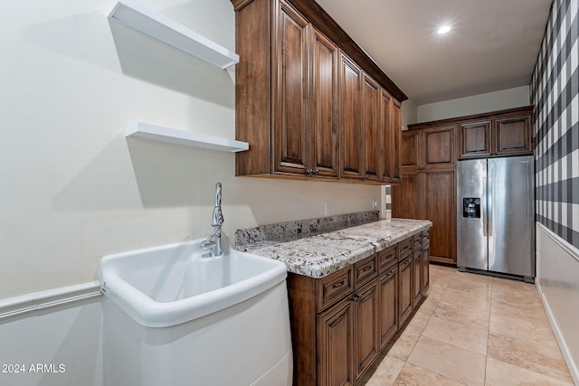 kitchen featuring light tile patterned flooring, dark brown cabinetry, stainless steel fridge with ice dispenser, and sink