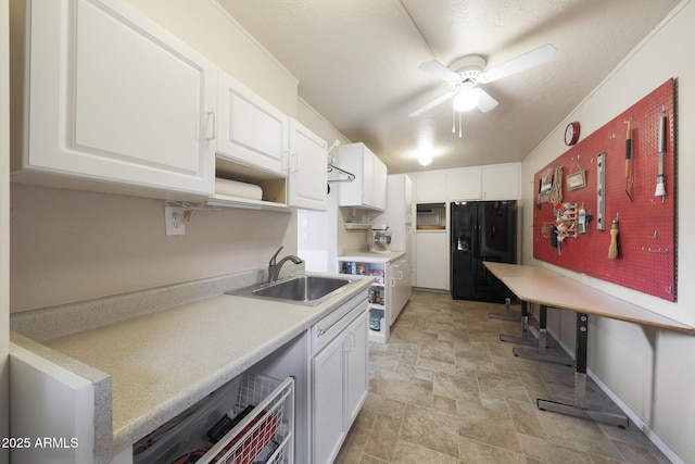 kitchen with stone finish floor, ceiling fan, a sink, light countertops, and black refrigerator with ice dispenser