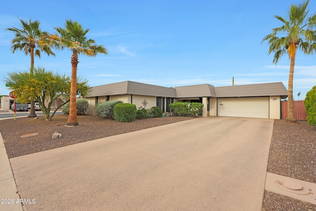 single story home featuring fence, an attached garage, and concrete driveway