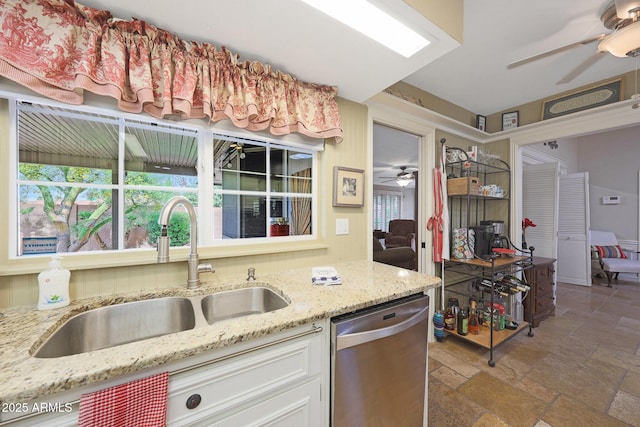 kitchen featuring stone tile floors, a ceiling fan, a sink, and dishwasher