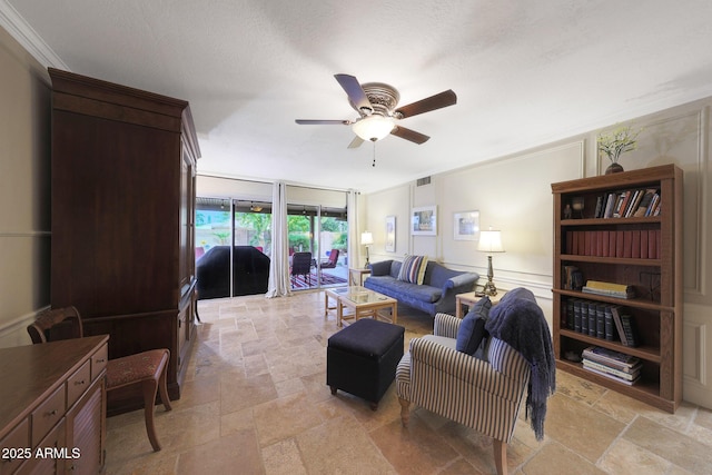 living area featuring visible vents, stone tile floors, ceiling fan, and crown molding