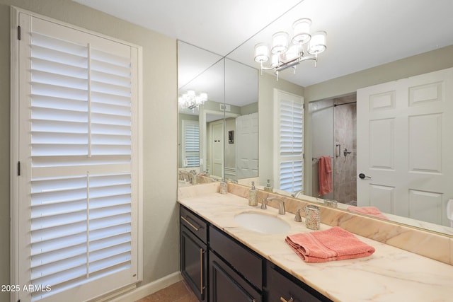 full bathroom with an inviting chandelier, baseboards, walk in shower, and vanity