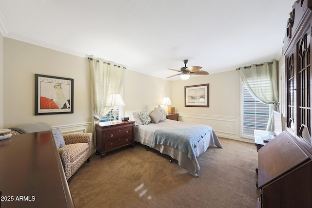 carpeted bedroom with ceiling fan, wainscoting, and ornamental molding