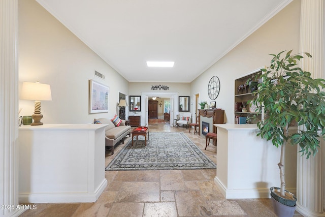 living room featuring stone tile floors, a lit fireplace, crown molding, and visible vents