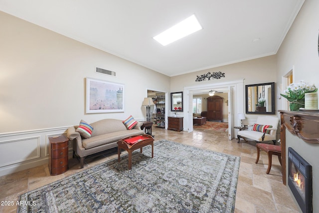 living area featuring visible vents, crown molding, and stone tile flooring