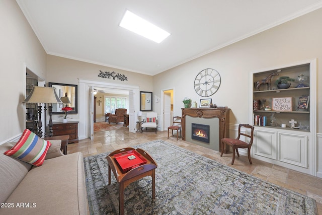 living area featuring crown molding, baseboards, a fireplace with flush hearth, and stone tile floors