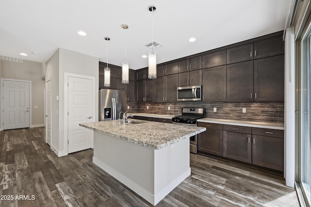 kitchen with sink, dark brown cabinets, pendant lighting, stainless steel appliances, and a kitchen island with sink