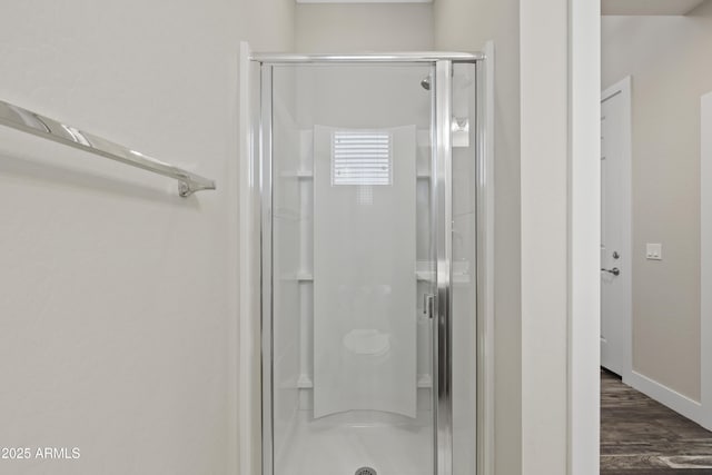 bathroom with wood-type flooring and a shower with shower door