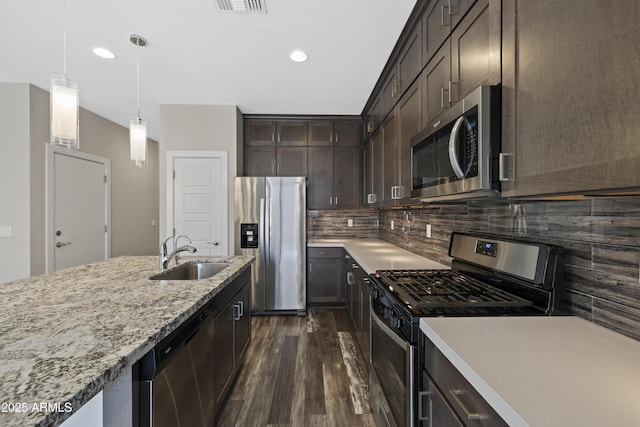 kitchen with dark brown cabinetry, sink, decorative light fixtures, appliances with stainless steel finishes, and dark hardwood / wood-style flooring