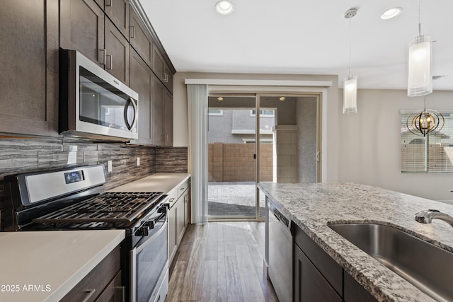 kitchen featuring sink, backsplash, dark brown cabinets, stainless steel appliances, and light hardwood / wood-style floors