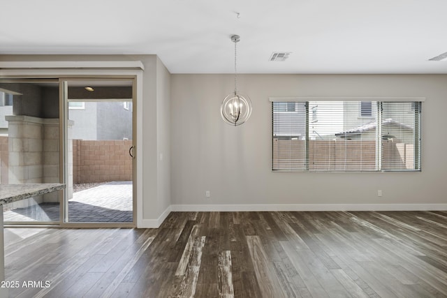 unfurnished room featuring an inviting chandelier and dark hardwood / wood-style flooring