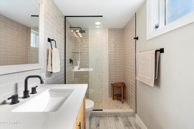 bathroom featuring hardwood / wood-style flooring, toilet, sink, and a tile shower