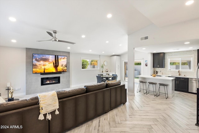 living room featuring ceiling fan, a fireplace, sink, and light parquet floors