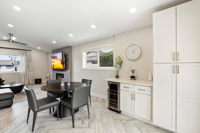 dining space featuring wine cooler, a fireplace, light parquet flooring, and a healthy amount of sunlight