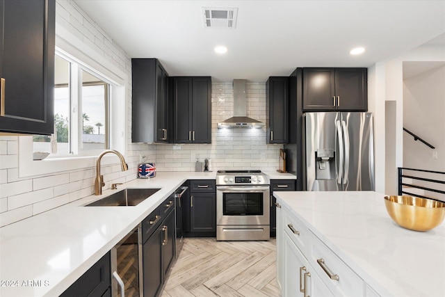 kitchen featuring sink, white cabinetry, appliances with stainless steel finishes, wall chimney range hood, and light parquet floors