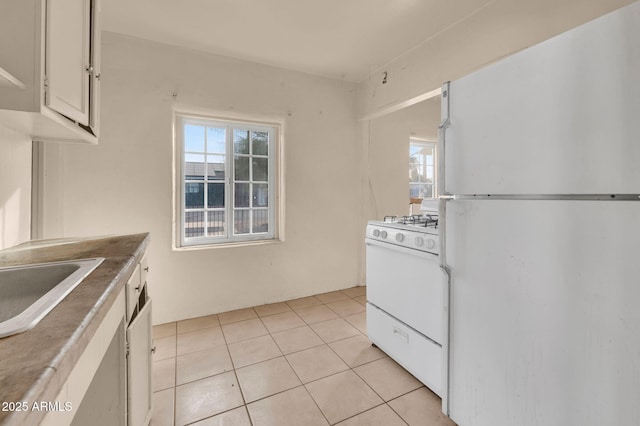 kitchen with light tile patterned floors, white cabinets, white appliances, and sink