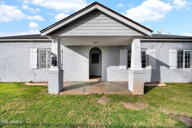 entrance to property featuring a lawn and a patio