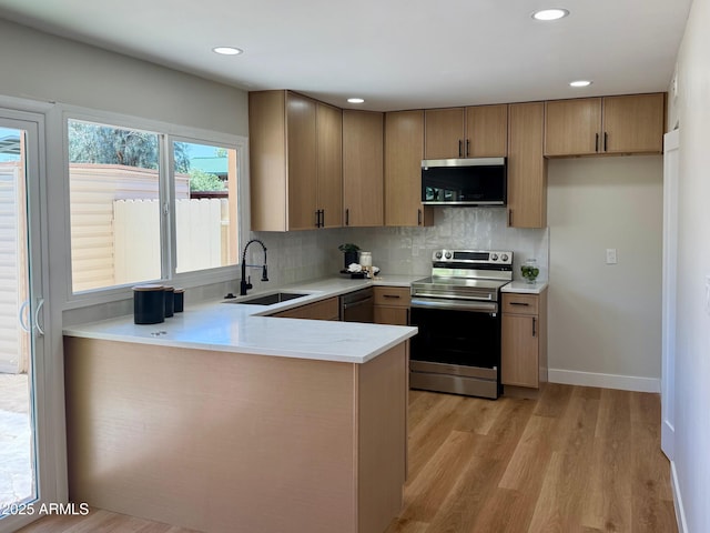 1061 E Fremont Dr, Tempe, AZ 85282 - kitchen with stainless steel appliances, light wood-style floors, tasteful backsplash, a peninsula, and recessed lighting
