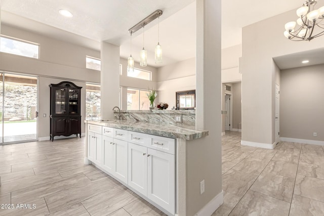 14058 S 24th Way, Phoenix, AZ 85048 - kitchen featuring a towering ceiling, a chandelier, white cabinetry, light stone countertops, and decorative light fixtures