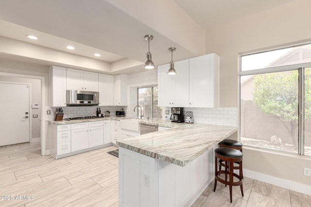 14058 S 24th Way, Phoenix, AZ 85048 - kitchen featuring appliances with stainless steel finishes, light stone countertops, white cabinets, a peninsula, and recessed lighting