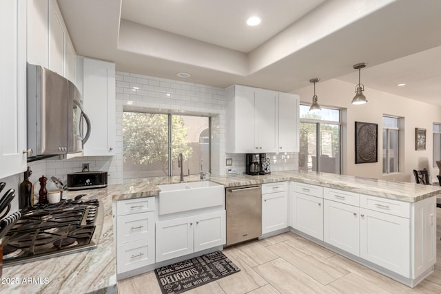 14058 S 24th Way, Phoenix, AZ 85048 - kitchen with appliances with stainless steel finishes, a peninsula, white cabinets, decorative backsplash, and light stone counters