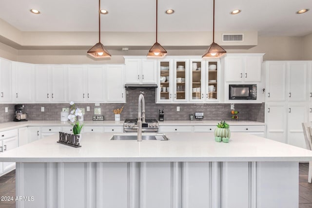 kitchen with a center island with sink, black microwave, and decorative light fixtures