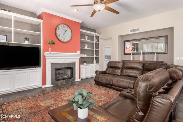 living room with ceiling fan, ornamental molding, built in shelves, and a tile fireplace