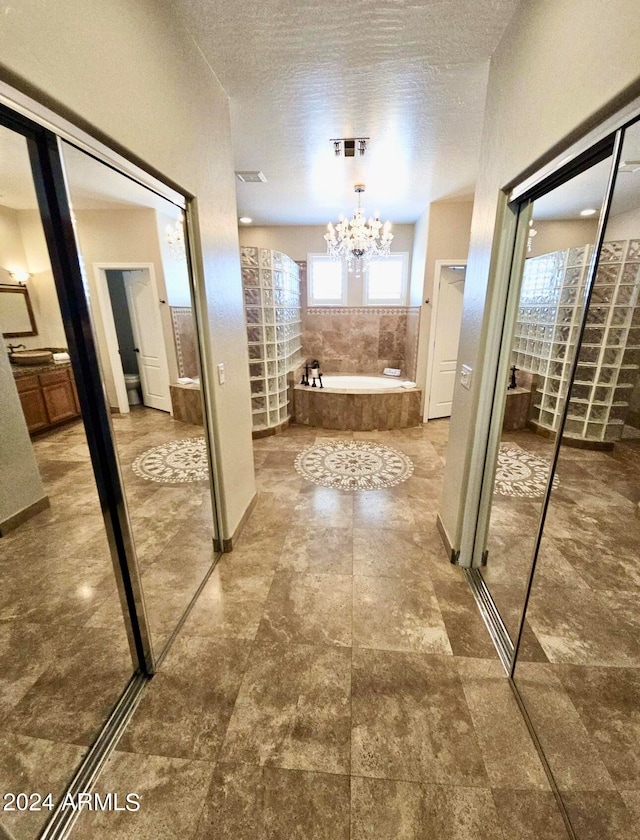 corridor featuring a textured ceiling and an inviting chandelier