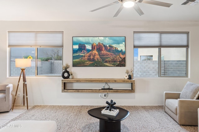 living area featuring tile patterned flooring, visible vents, and ceiling fan