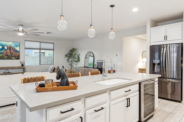 kitchen with beverage cooler, a center island with sink, stainless steel fridge with ice dispenser, a sink, and open floor plan