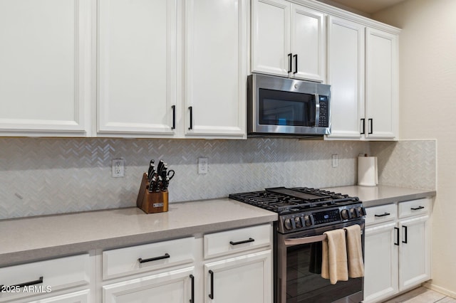 kitchen featuring stainless steel appliances, backsplash, and white cabinetry