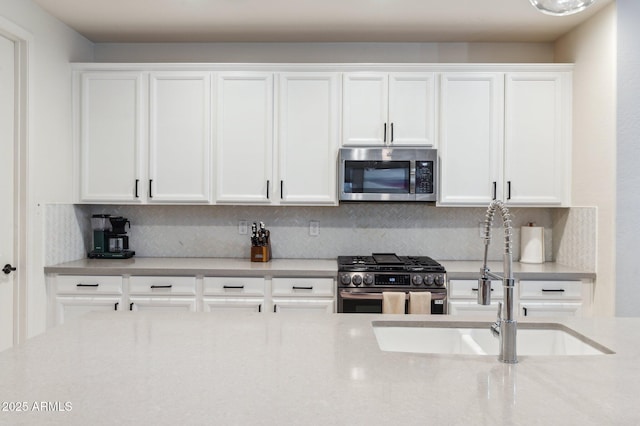 kitchen with a sink, decorative backsplash, appliances with stainless steel finishes, and white cabinets