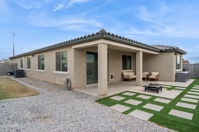 rear view of property featuring a fire pit, fence, stucco siding, cooling unit, and a patio