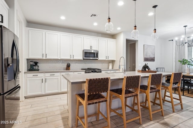 kitchen featuring visible vents, backsplash, light countertops, appliances with stainless steel finishes, and a sink