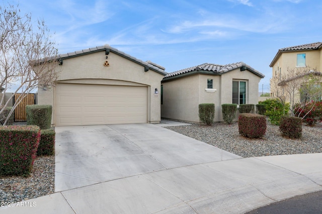 mediterranean / spanish-style house featuring stucco siding, concrete driveway, an attached garage, and a tiled roof