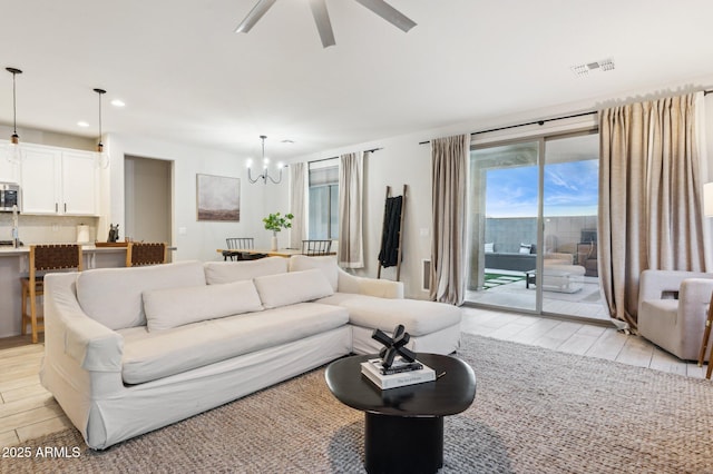 living area with recessed lighting, visible vents, light wood-style floors, and ceiling fan with notable chandelier