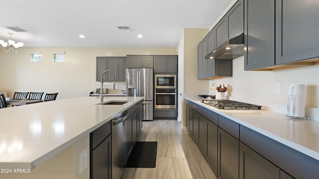 kitchen featuring sink, stainless steel appliances, a notable chandelier, gray cabinets, and exhaust hood